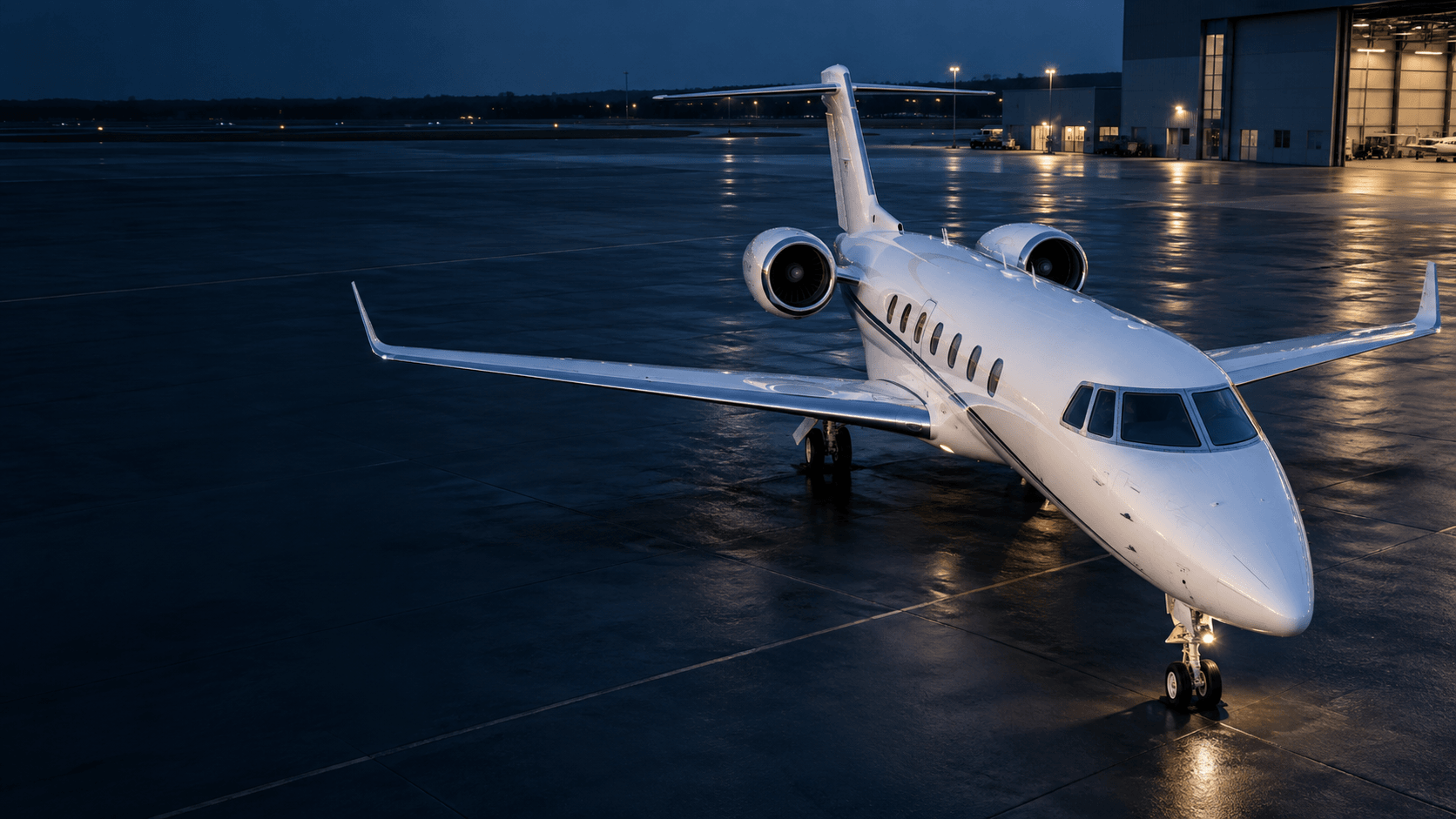 A business jet parked on an illuminated apron at dusk